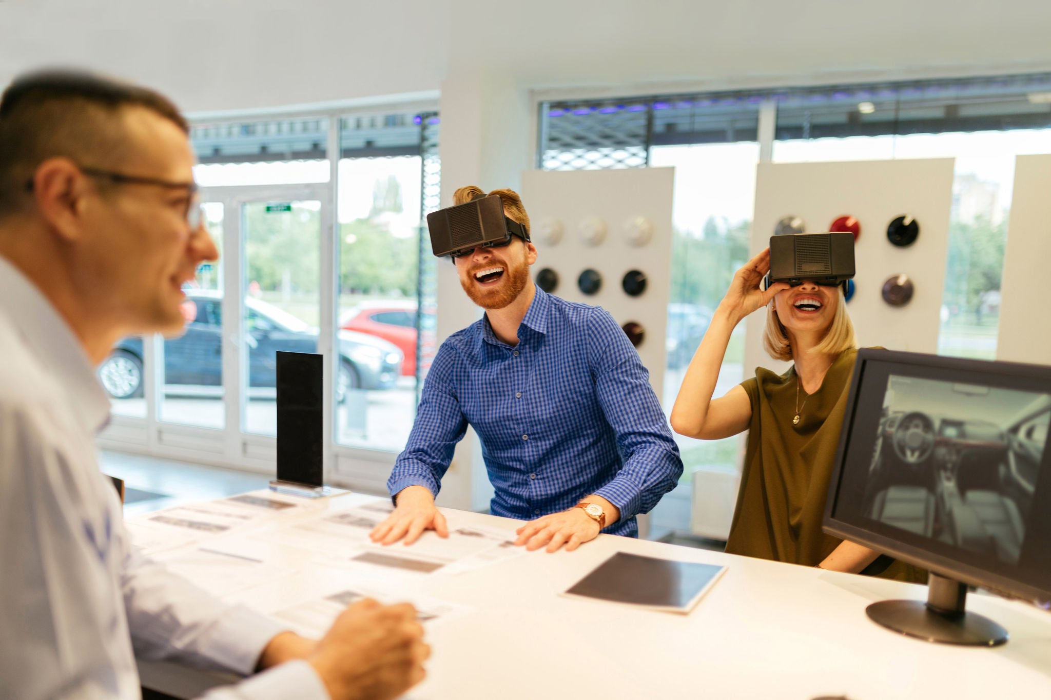 couple using vr glasses in car dealership