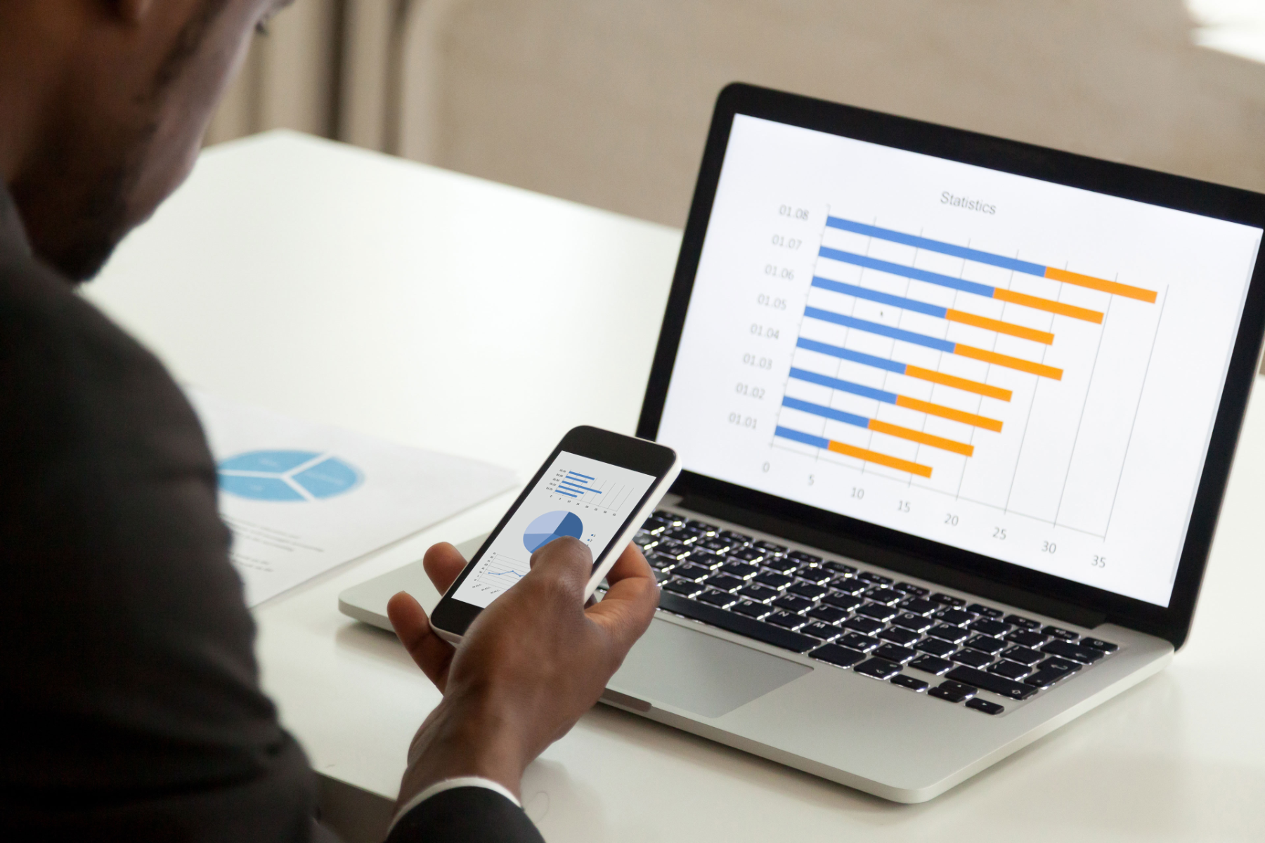 Man checking graphs on mobile and laptop