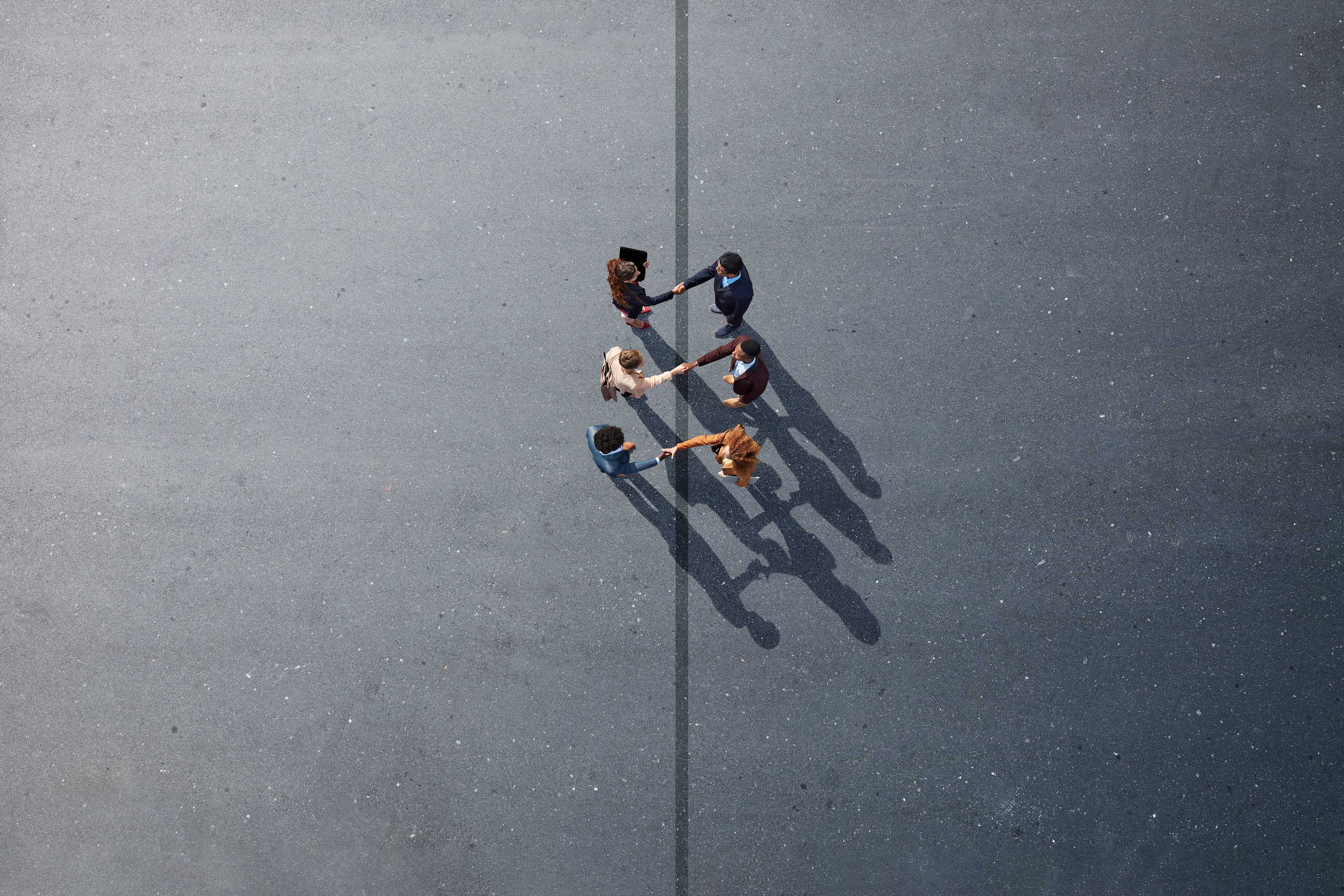 ey-businesspeople-making-handshakes-across-line-on-painted-asphalt