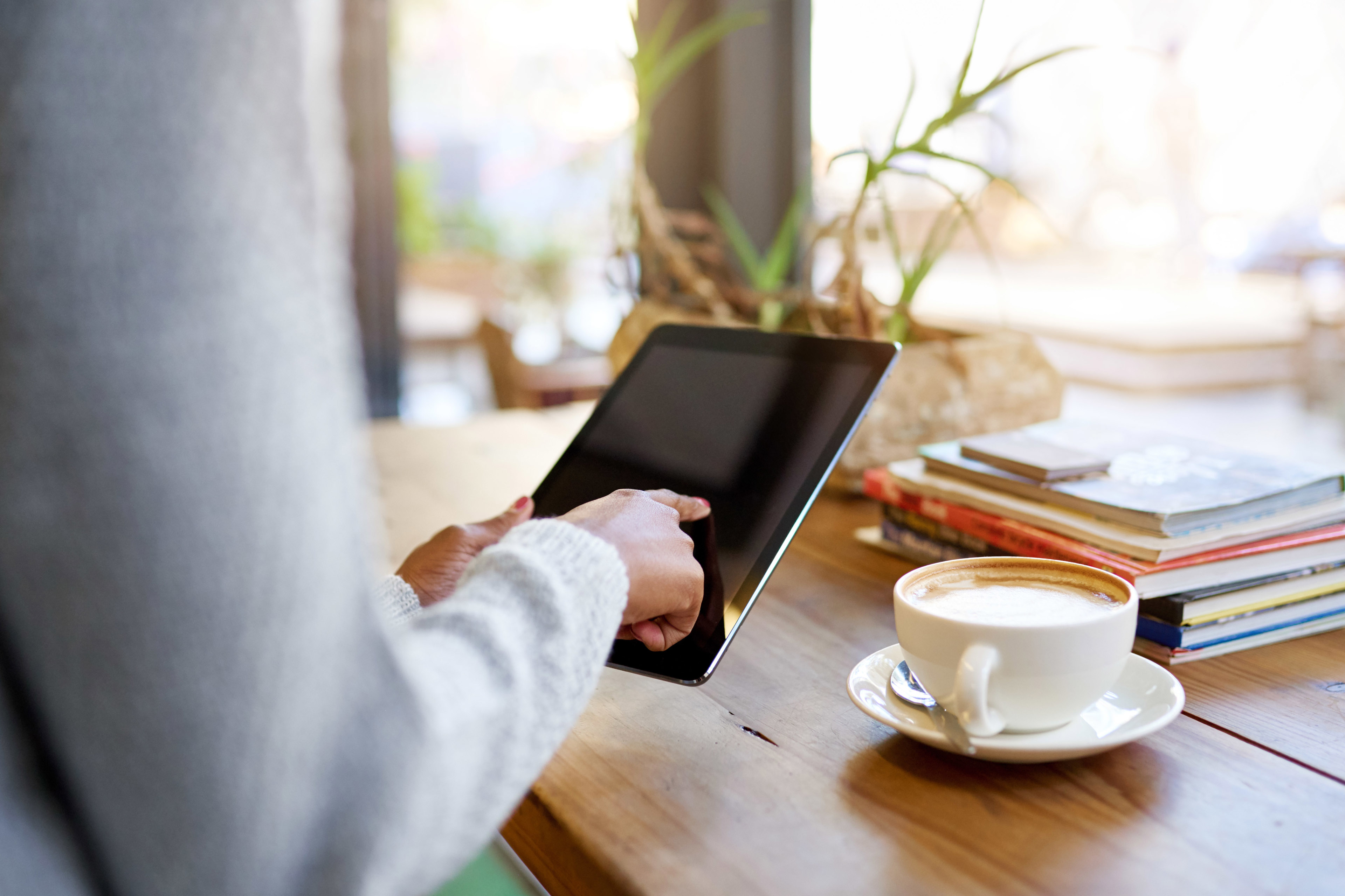 Closeup of a young woman sitting at a table in a cafe using a digital tablet